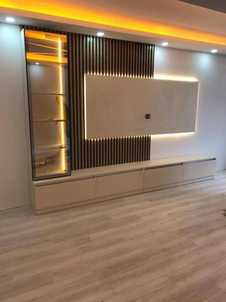 Built-in TV unit with fluted dark panelling, a backlit recess and a white cabinet run beneath